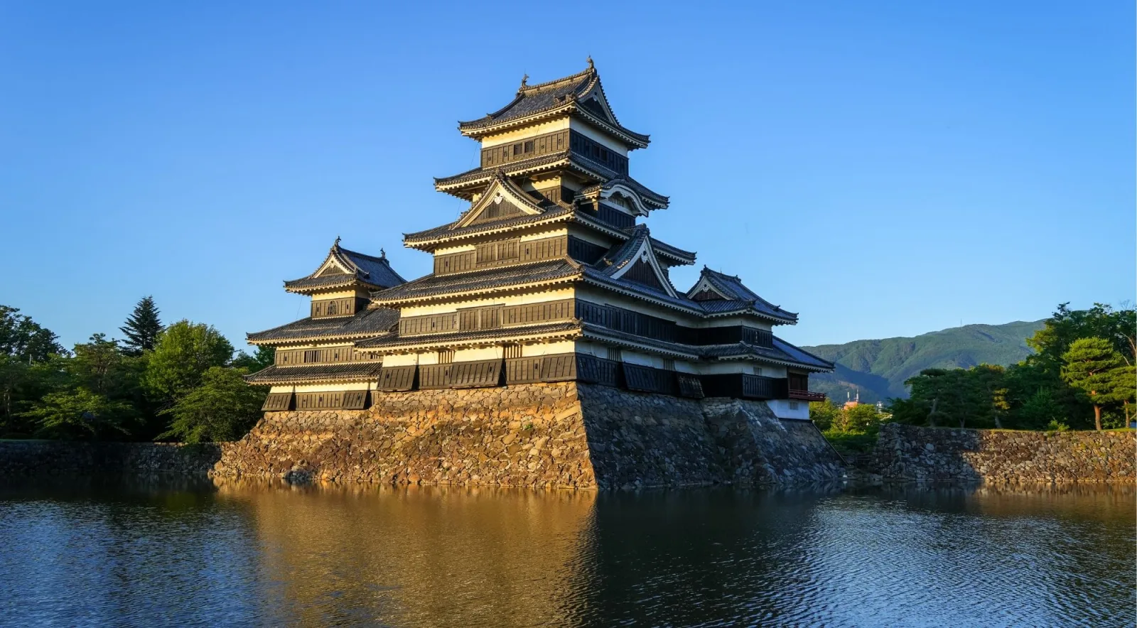 Matsumoto Castle's six-story keep viewed from across the moat with mountains behind