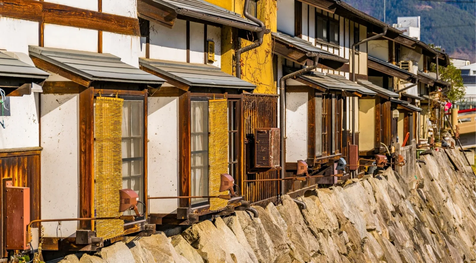 Traditional wooden merchant houses along a stone-walled street in the Matsumoto area